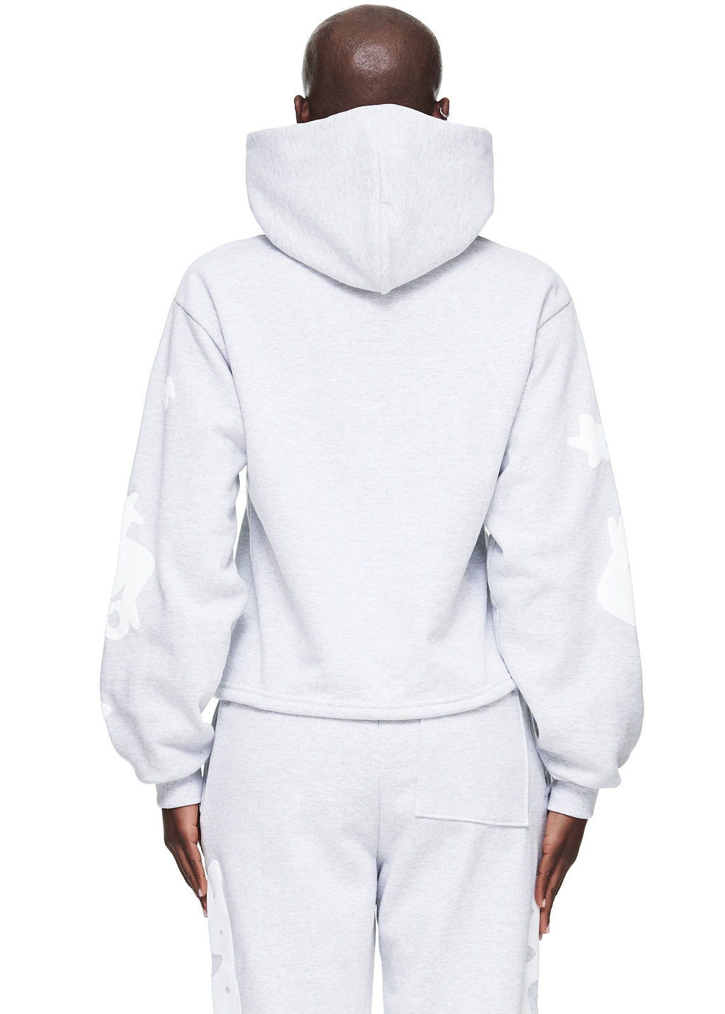 Back view of a model wearing a light gray cropped fleece hoodie with white puff print designs on the sleeves.