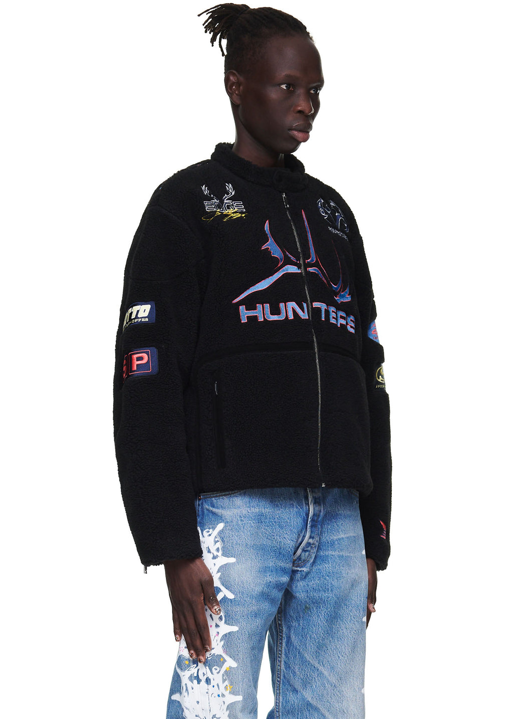 Black sherpa Hunter Moto jacket with colorful SP5DER patches, embroidery, zip closure, and welt pockets.