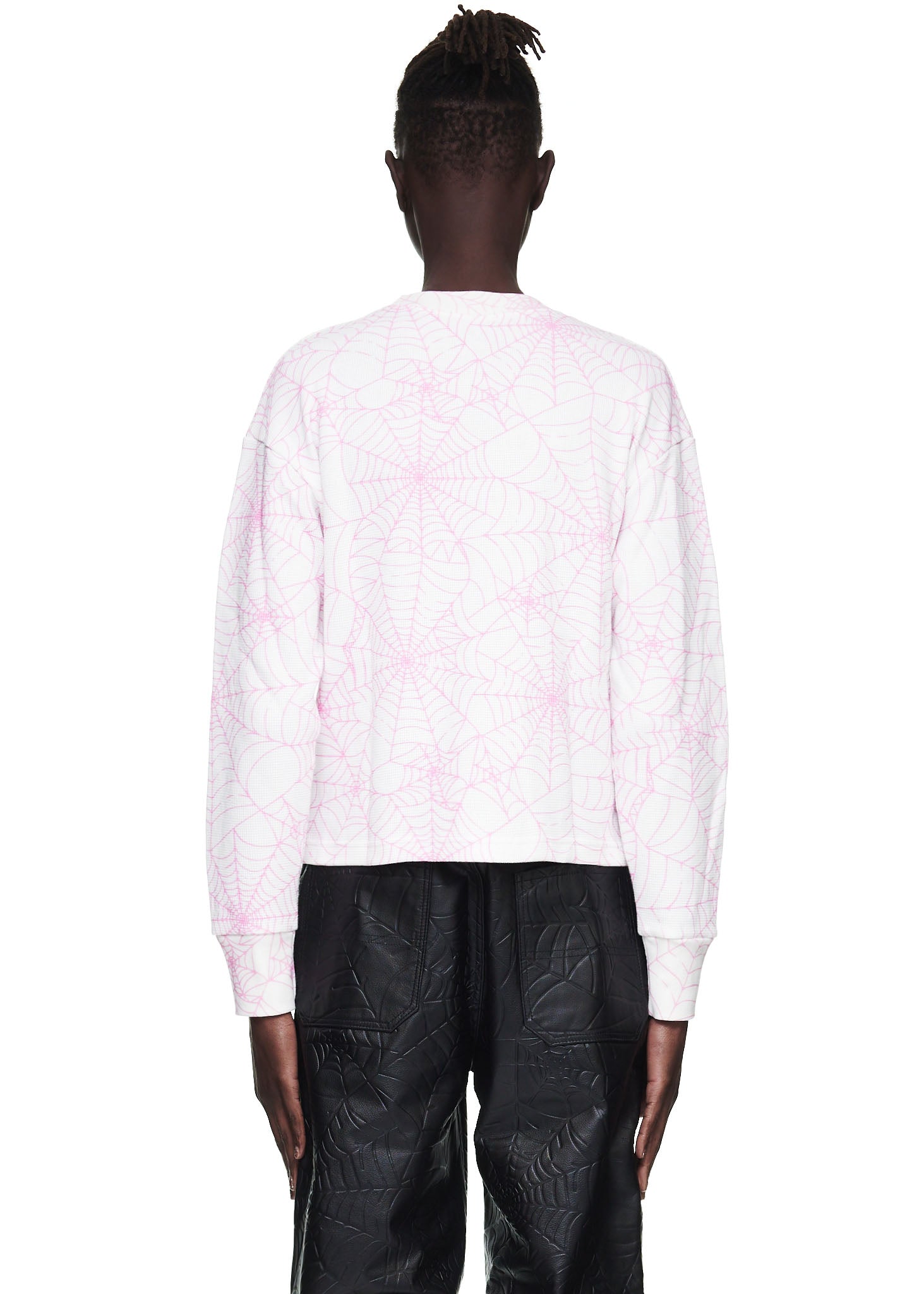 Back view of a male model wearing a white waffle thermal long sleeve shirt with an all-over pink spiderweb print.