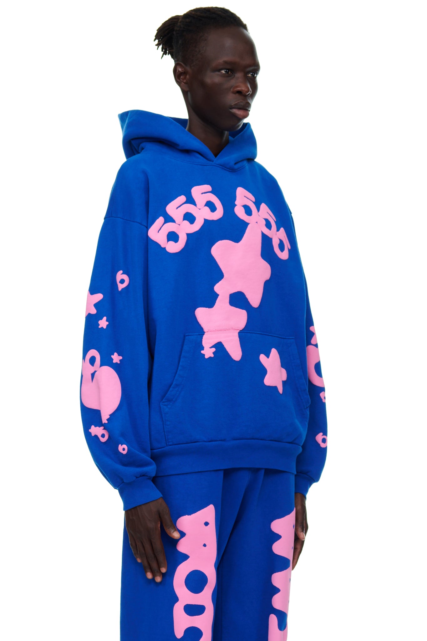 Male model in a blue fleece hoodie with pink puff print '555' and star graphics, worn with matching sweatpants.