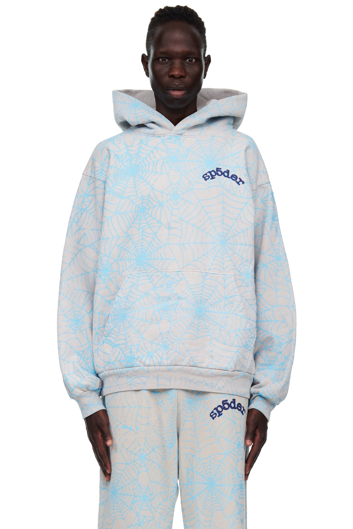 Man in a grey fleece hoodie with all-over light blue cracked spider web print and "SP5DER" text.
