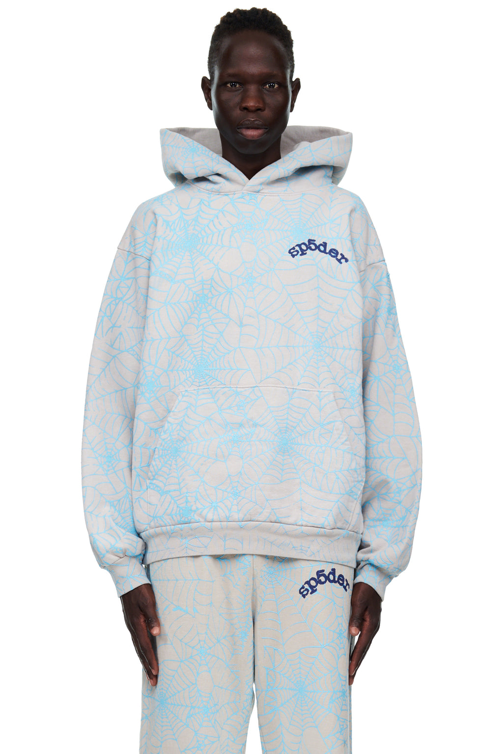 Man in a grey fleece hoodie with all-over light blue cracked spider web print and "SP5DER" text.