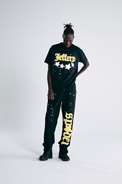 Black heavyweight cotton tee with yellow "Jeffery" script and star puff print, paired with matching sweatpants.