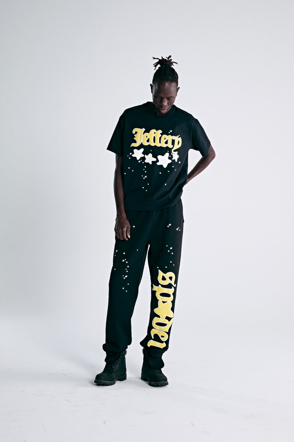 Black heavyweight cotton tee with yellow "Jeffery" script and star puff print, paired with matching sweatpants.
