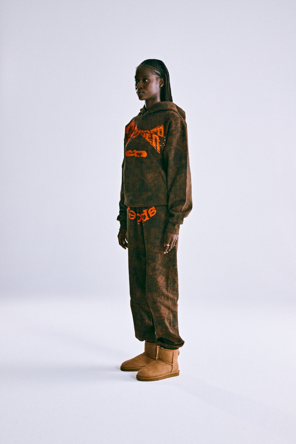 Model in T&F TREE CAMO HOODIE and matching sweatpants, featuring orange puff print text.