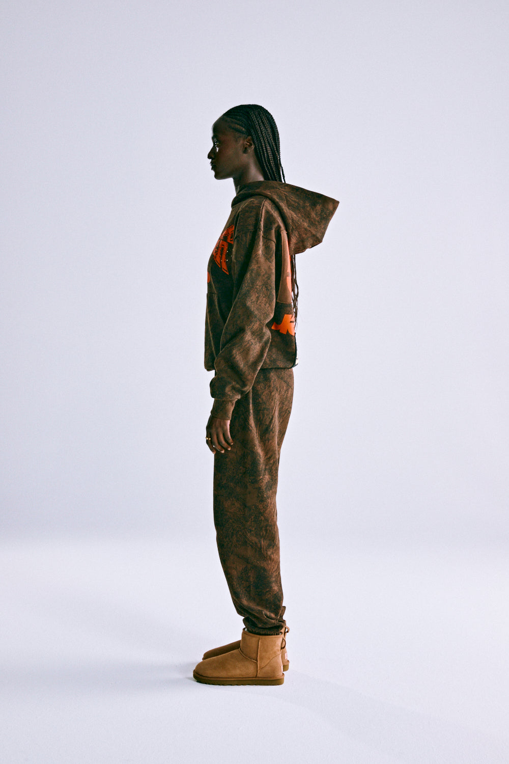 Woman in T&F TREE CAMO HOODIE and matching sweatpants, featuring orange puff print and custom patch.