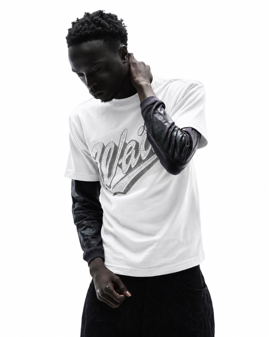Model wearing a white graphic t-shirt with black long sleeves and dark jeans against a white background.