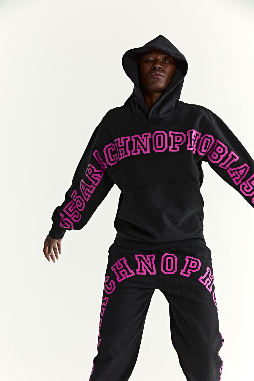 Black cotton fleece hoodie and sweatpants with pink "TECHNOPHOBIA" puff print.