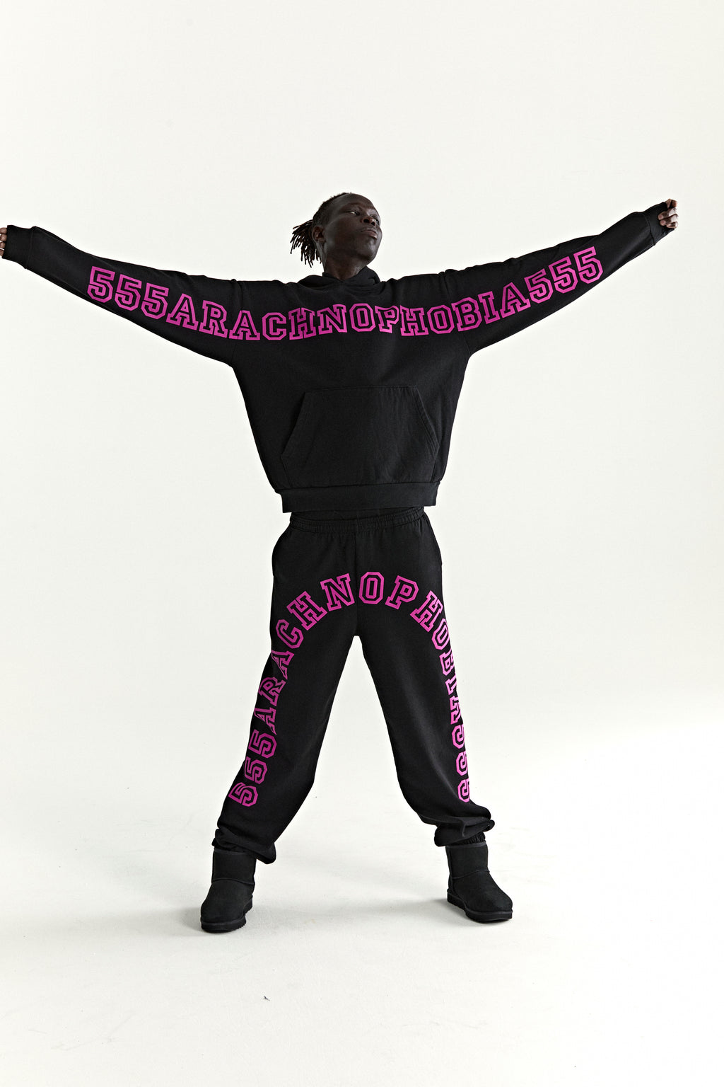 Black cotton fleece hoodie and sweatpants set with bold pink "555ARACHNOPHOBIA555" text.
