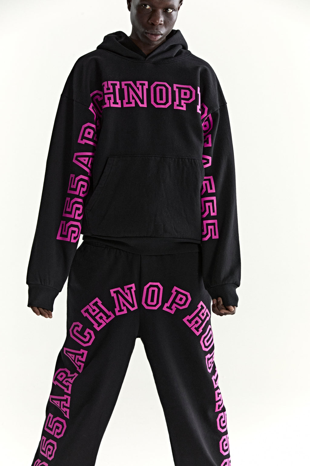 Black ARACH HOODIE and sweatpants set with bold pink puff print text on chest, arms, and legs.