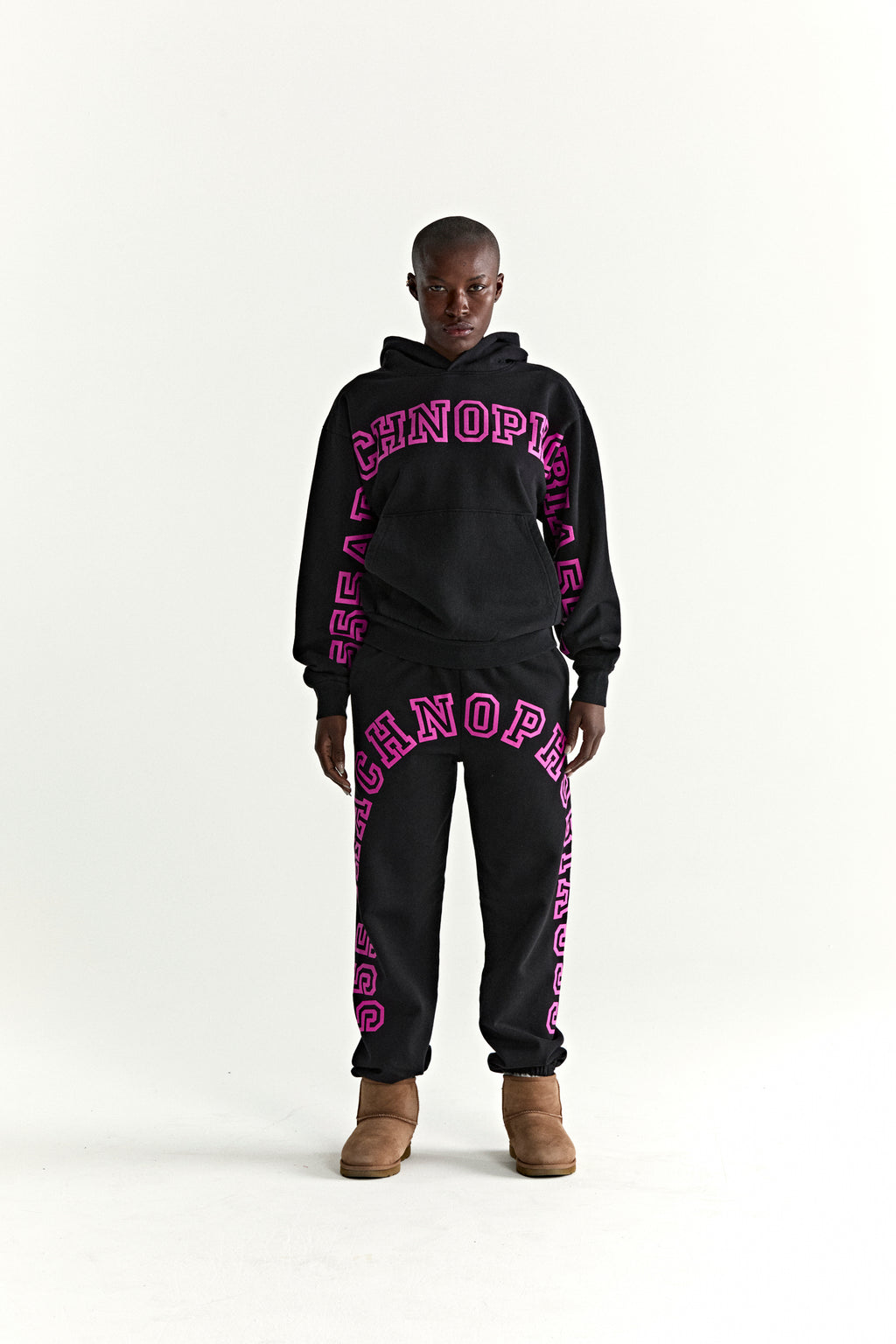 Black ARACH HOODIE and sweatpants set with bold pink puff print text, kangaroo pocket, and rib knit details.
