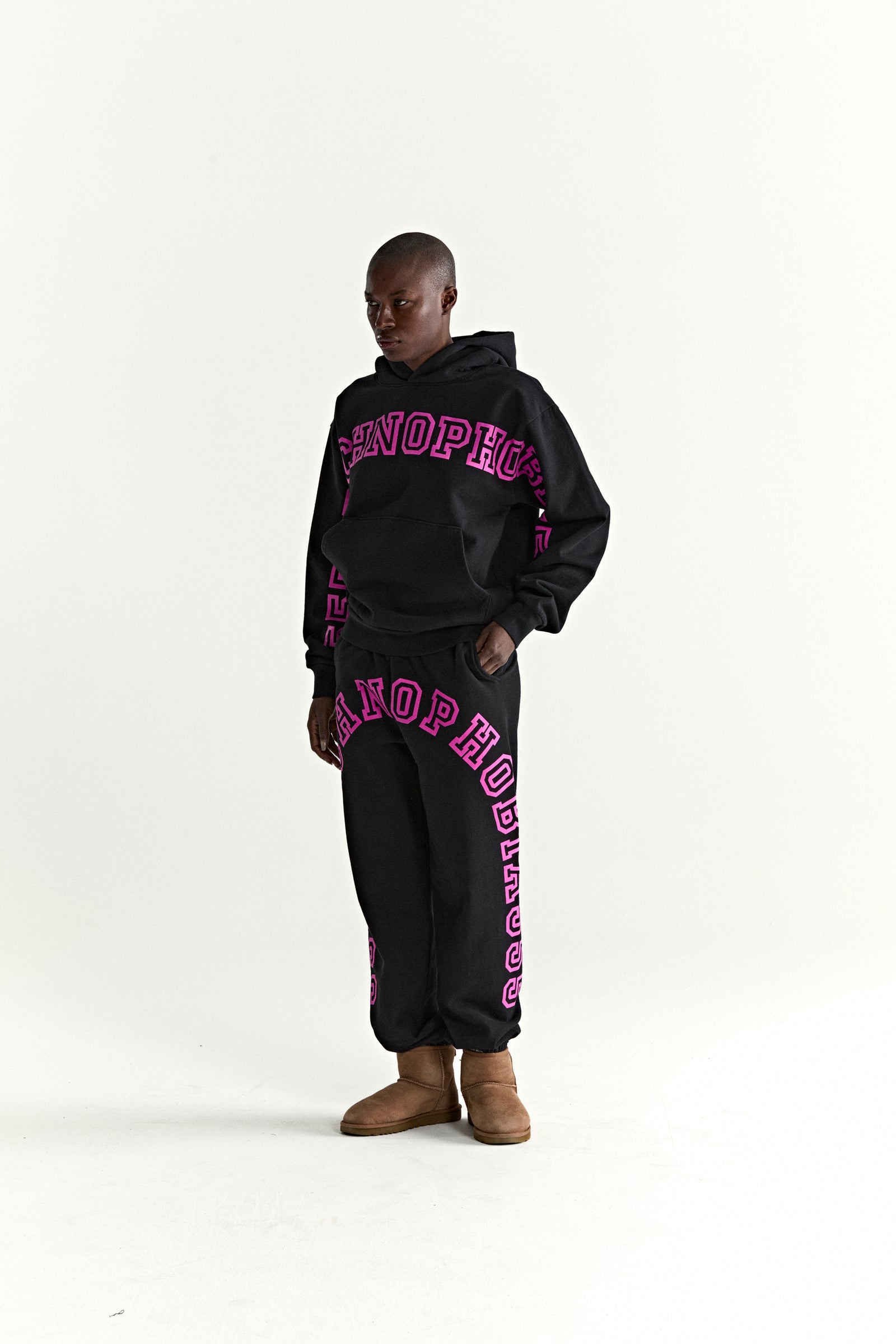 Black cotton fleece hoodie and sweatpants with pink puff print text, kangaroo pocket, and rib knit details.