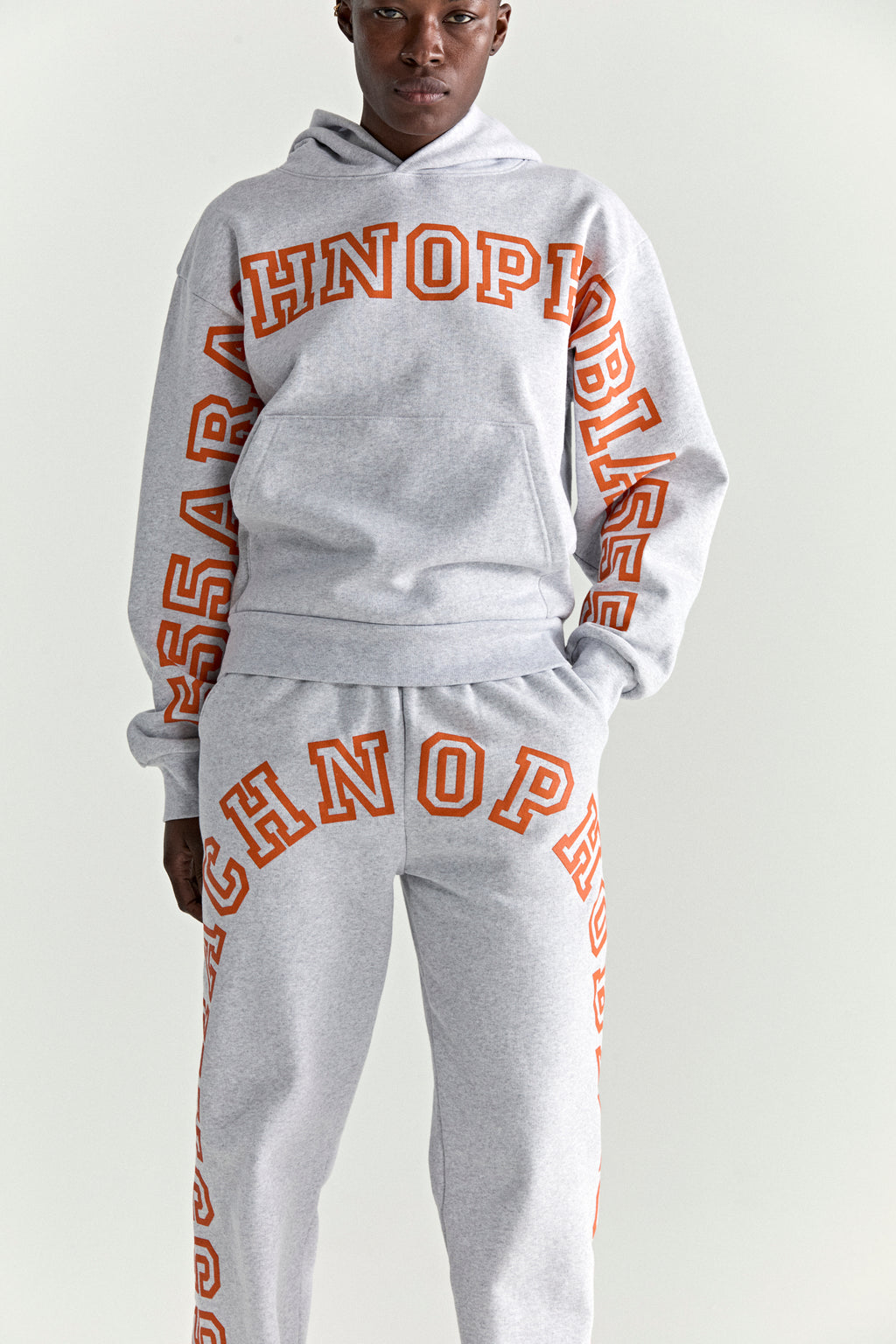 Grey ARACH HOODIE and sweatpants with orange puff print text, kangaroo pocket, and rib knit cuffs.
