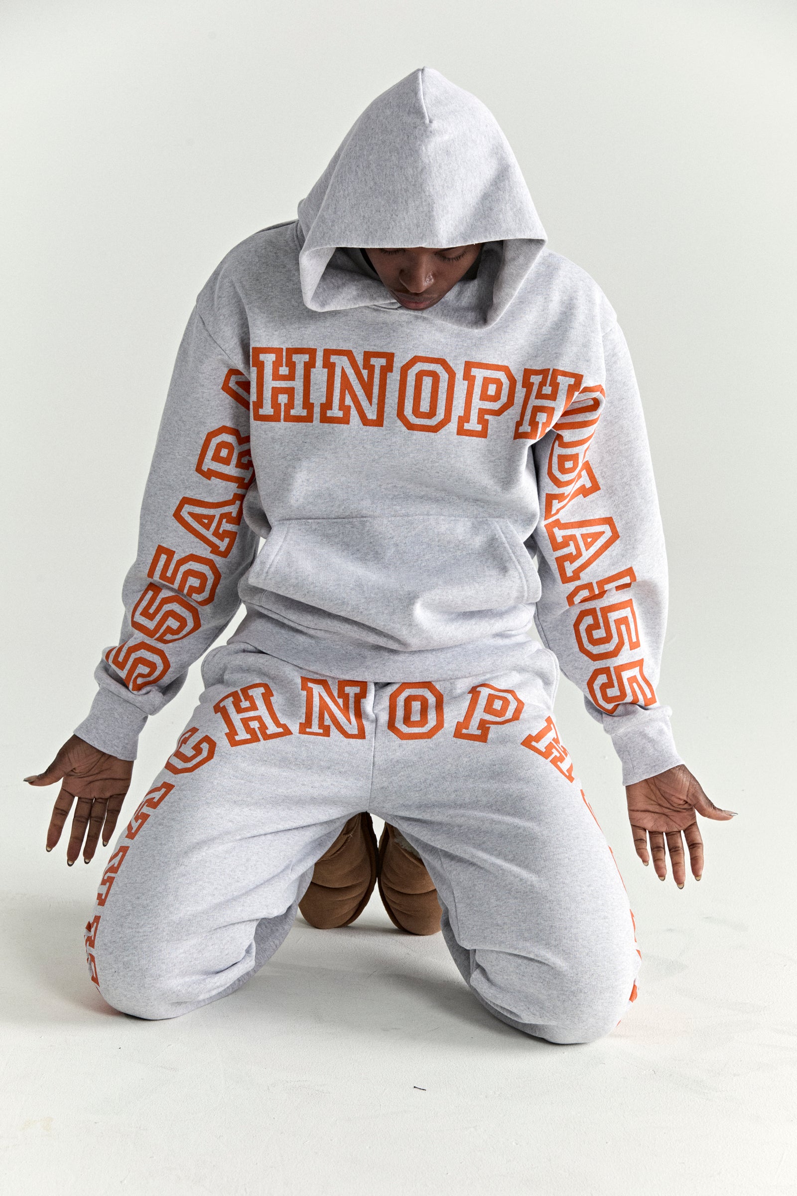 Grey 13oz cotton fleece hoodie and sweatpants with orange puff print text.