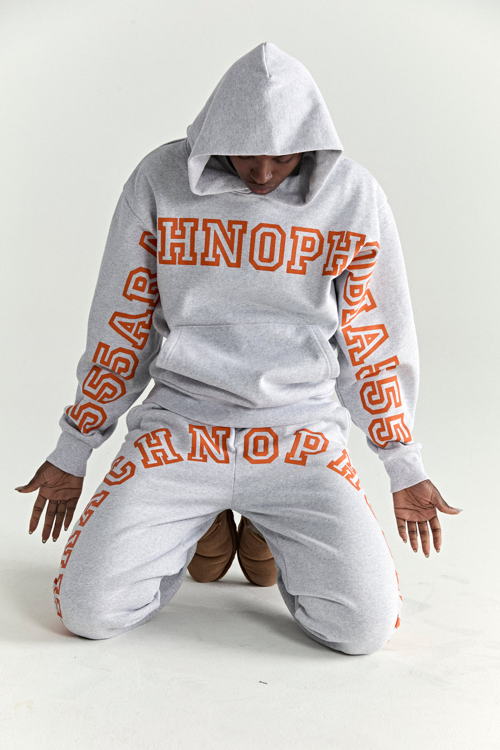Grey 13oz cotton fleece hoodie and sweatpants with orange puff print text.