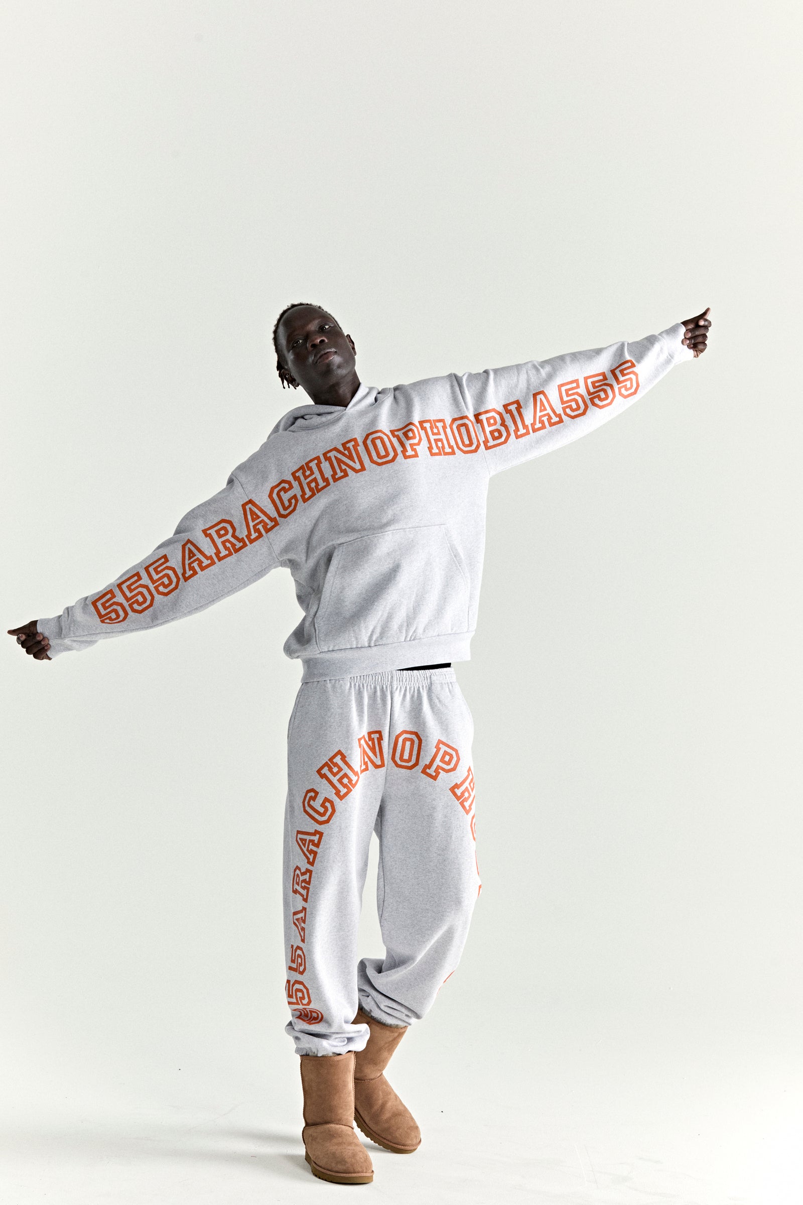 Grey ARACH HOODIE and sweatpants with orange puff print text, worn by a model.