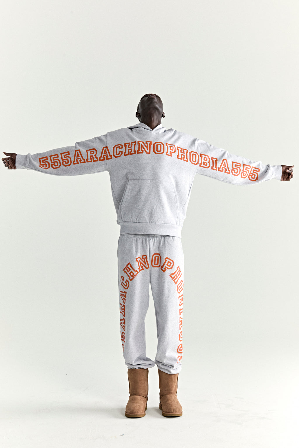 Grey 13oz cotton fleece hoodie and sweatpants with orange "555ARACHNOPHOBIA555" puff print.