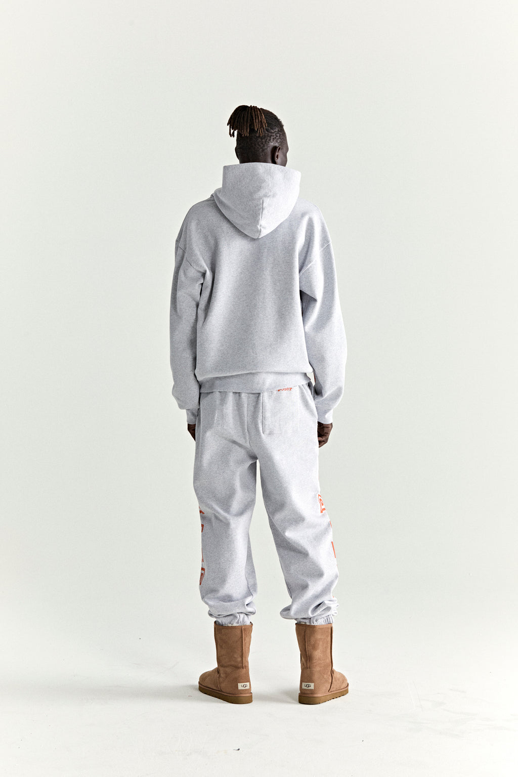 ARACH HOODIE: Grey 13oz cotton fleece hoodie and sweatpants with red text print, worn by a person from behind.