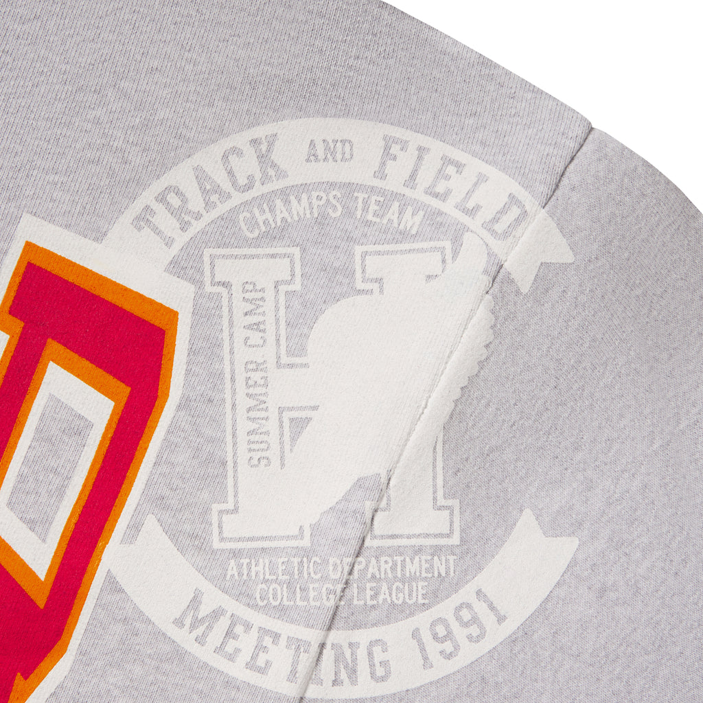 Grey 13oz cotton fleece zip hoodie featuring a varsity-inspired Track and Field graphic print in white, orange, and red.
