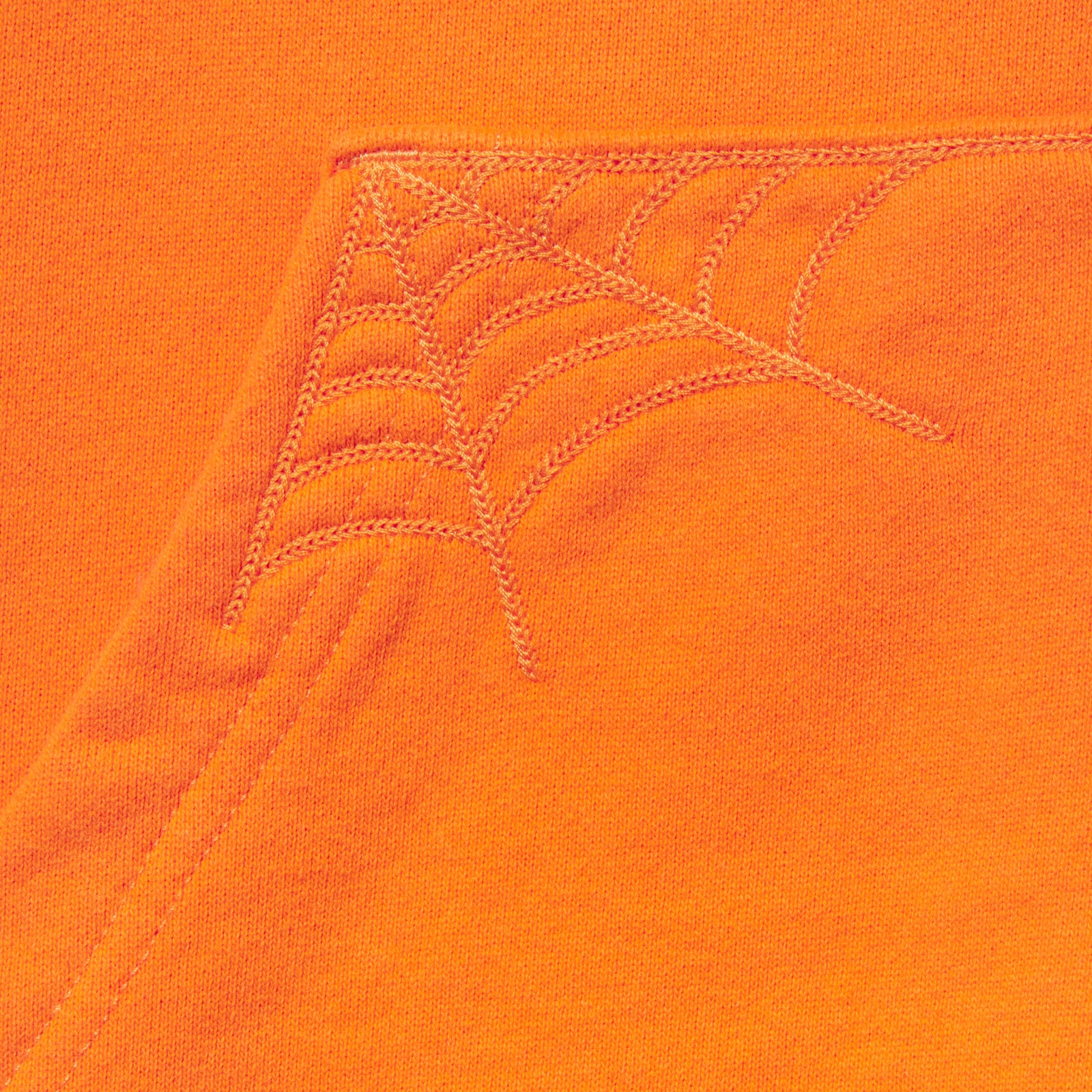 Bright orange 13oz cotton fleece zip hoodie featuring detailed spider web embroidery on the front pocket corner.