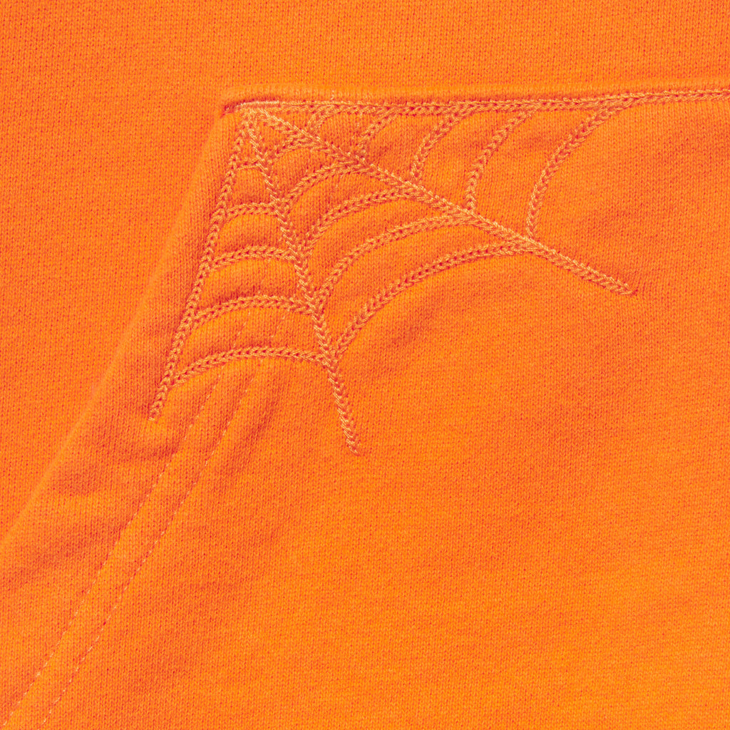 Bright orange 13oz cotton fleece zip hoodie featuring detailed spider web embroidery on the front pocket corner.