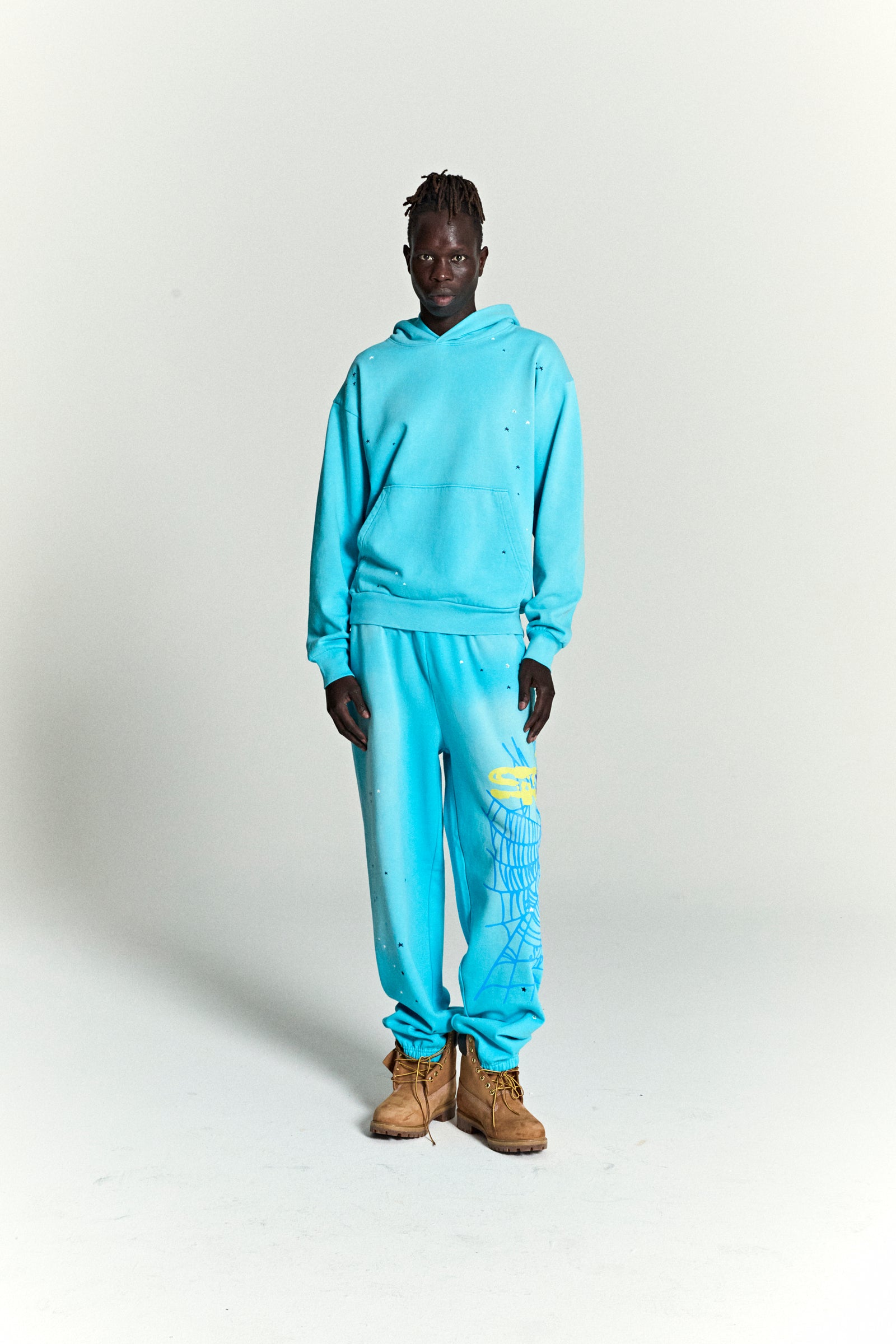 Turquoise HEAVY WEB HOODIE and sweatpants with scattered star print and web print.