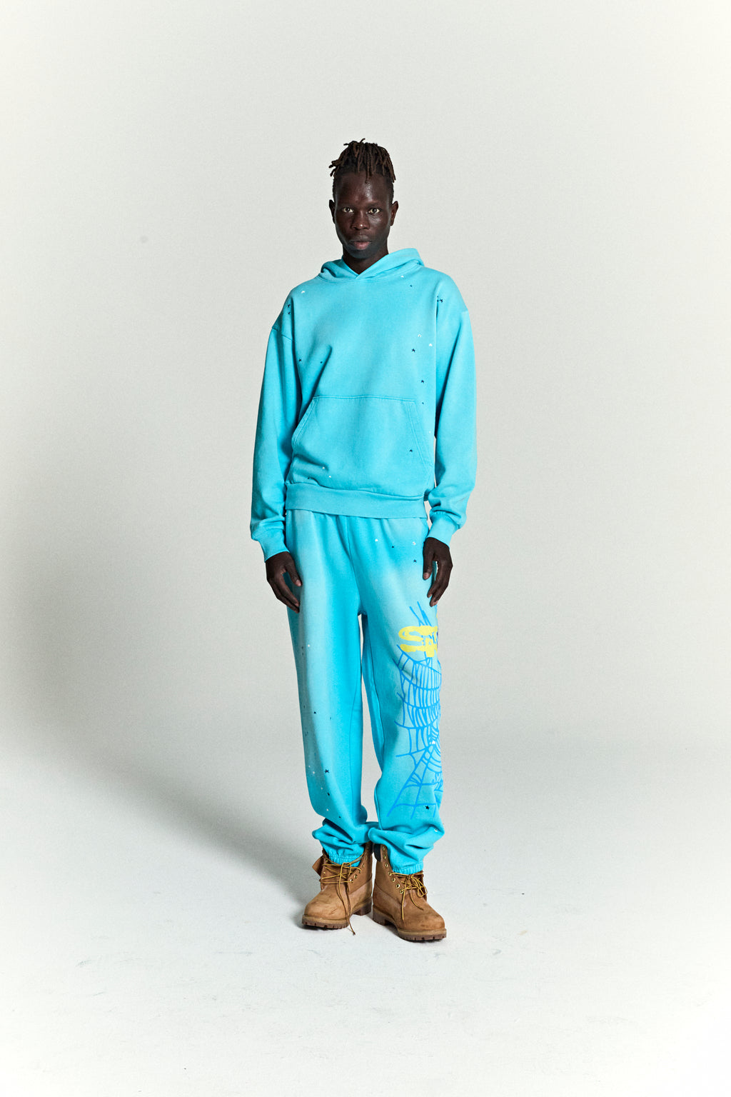 Turquoise HEAVY WEB HOODIE and sweatpants with scattered star print and web print.