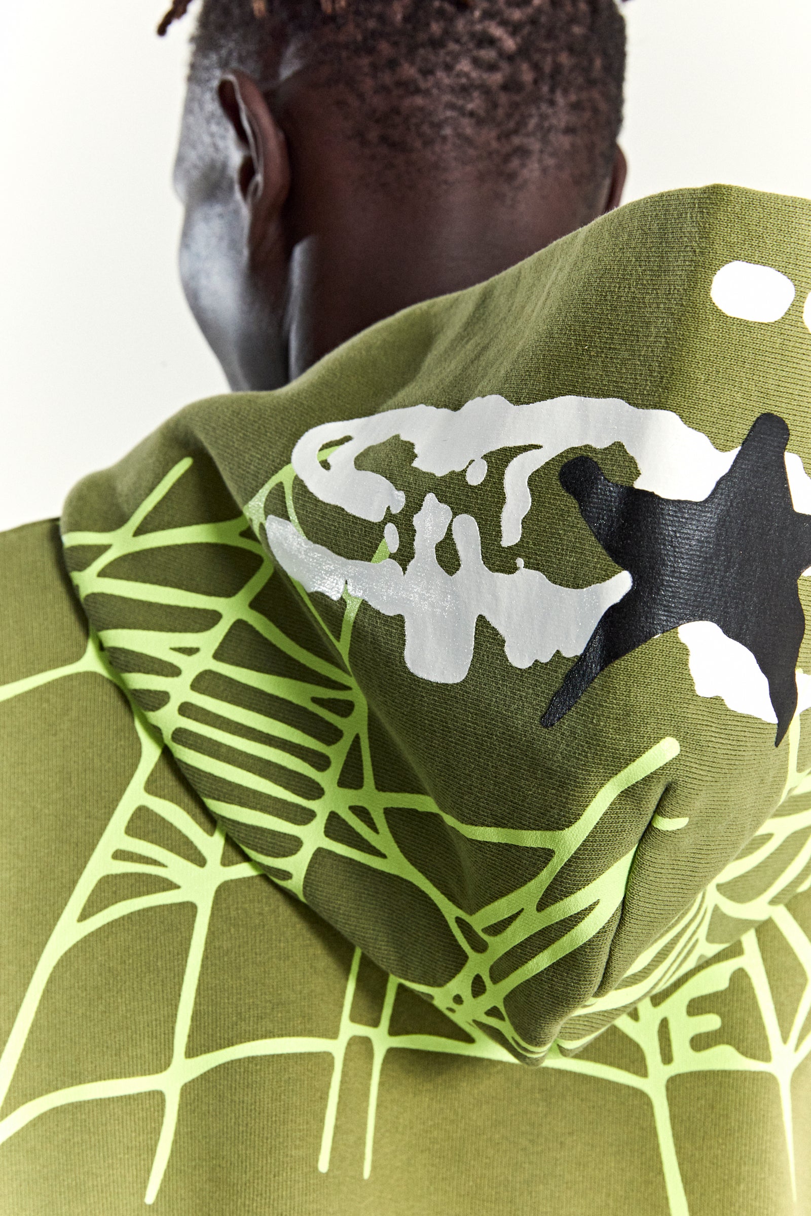 Olive green heavy web hoodie with neon green web print and white/black star puff print on the hood.
