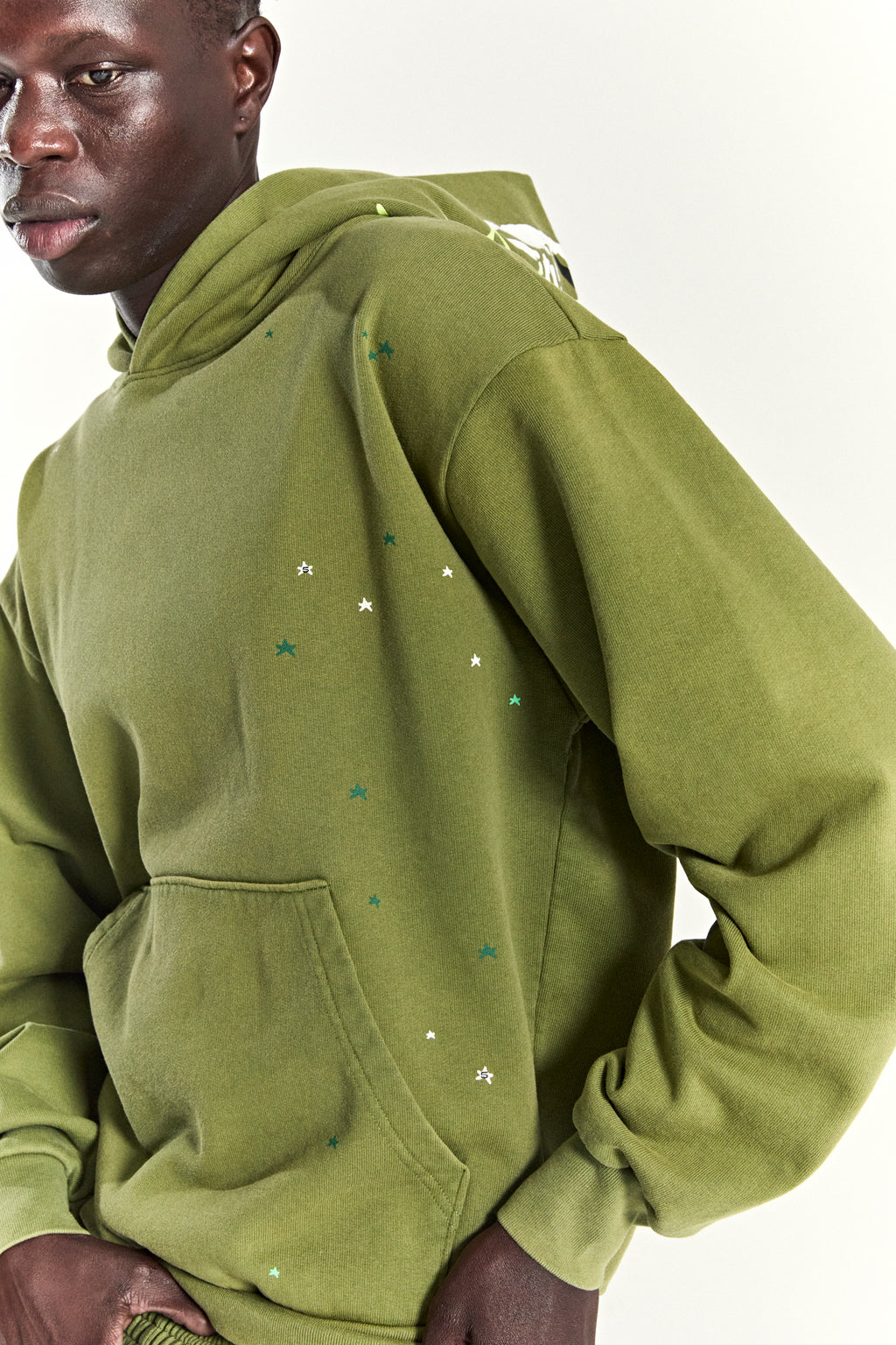 Olive green heavy web hoodie with scattered star print and kangaroo pocket.