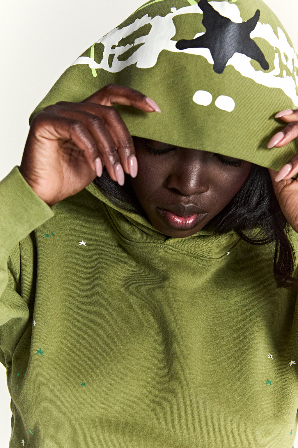 Green cotton fleece hoodie with scattered star print and web print on the hood.