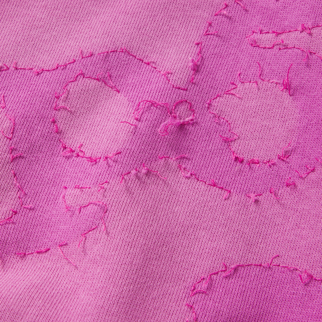 Close-up of pink 100% cotton fleece hoodie featuring distressed star graphic print with raw-edge stitched applique detail.