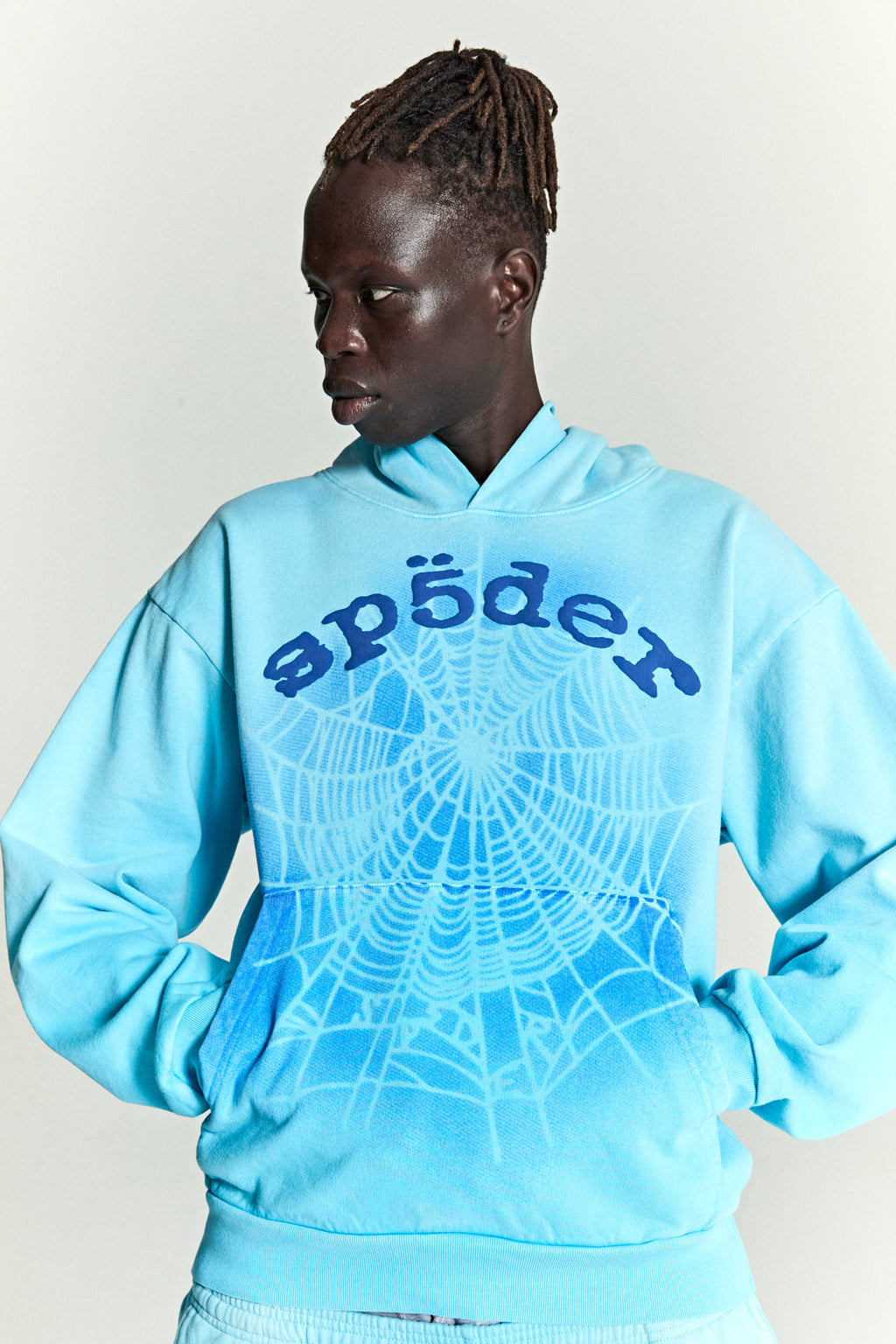 Light blue cotton fleece hoodie with "sp5der" text and a spray web V2 graphic on the front.