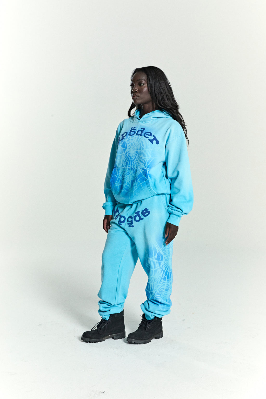 Model in OG Web V2 Spray Hoodie and matching sweatpants, light blue 100% cotton fleece with puff print spiderweb design.