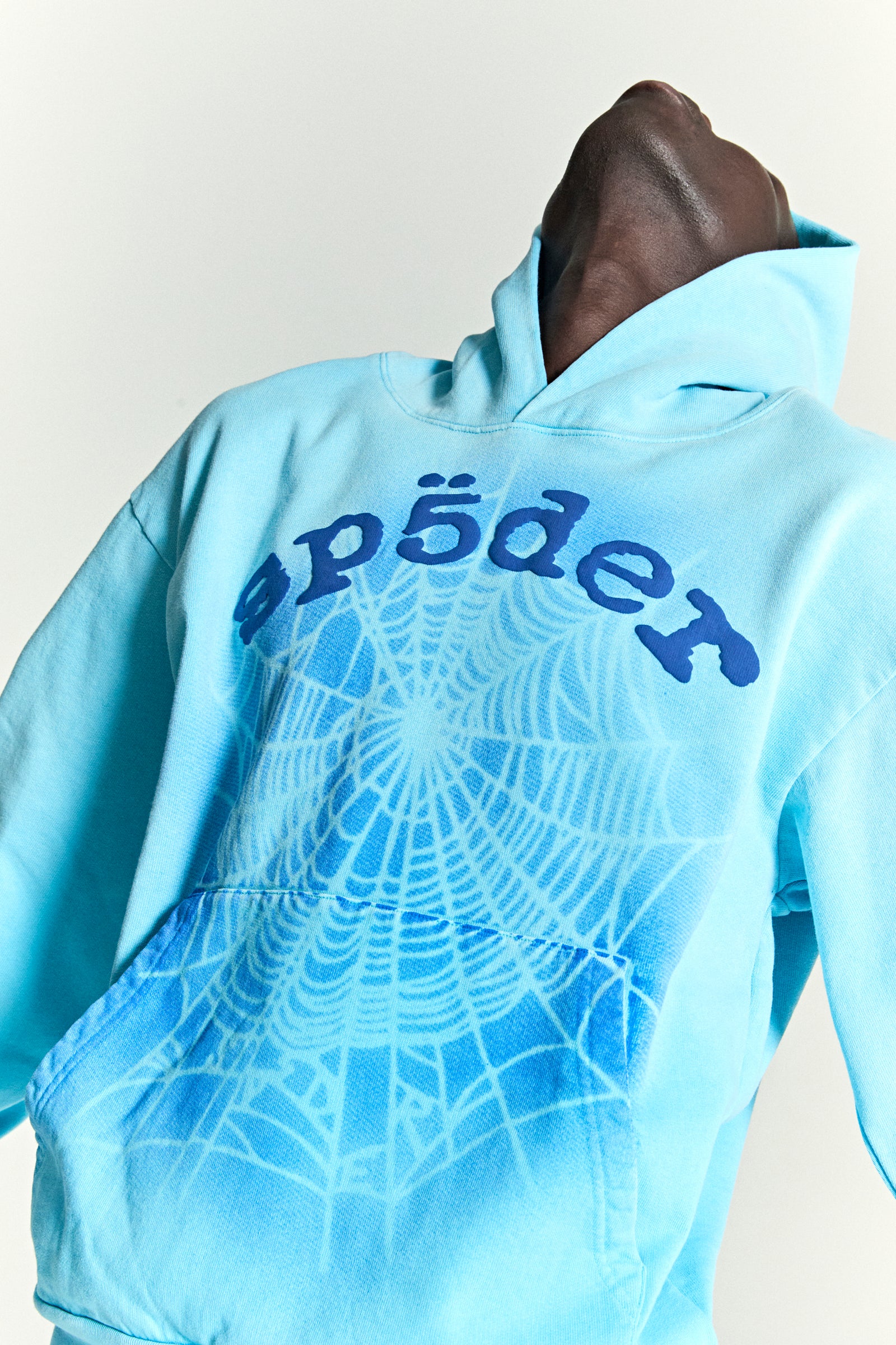 Light blue cotton fleece hoodie with "sp5der" text and a spray web V2 print on the front.