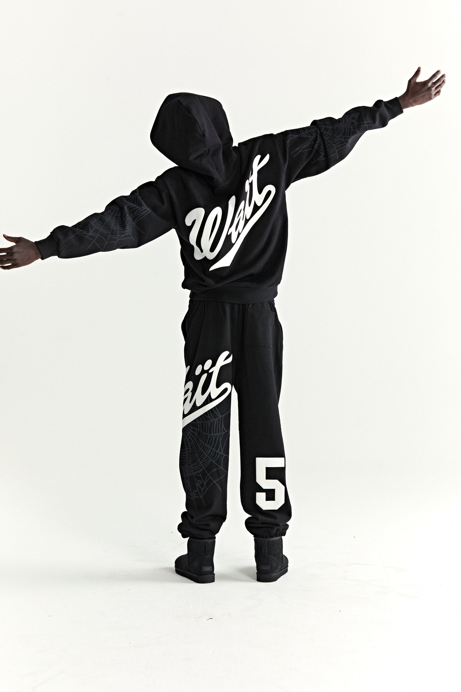 Black 13oz cotton fleece hoodie and sweatpants with "Wait" script, "5" graphic, and web detail.