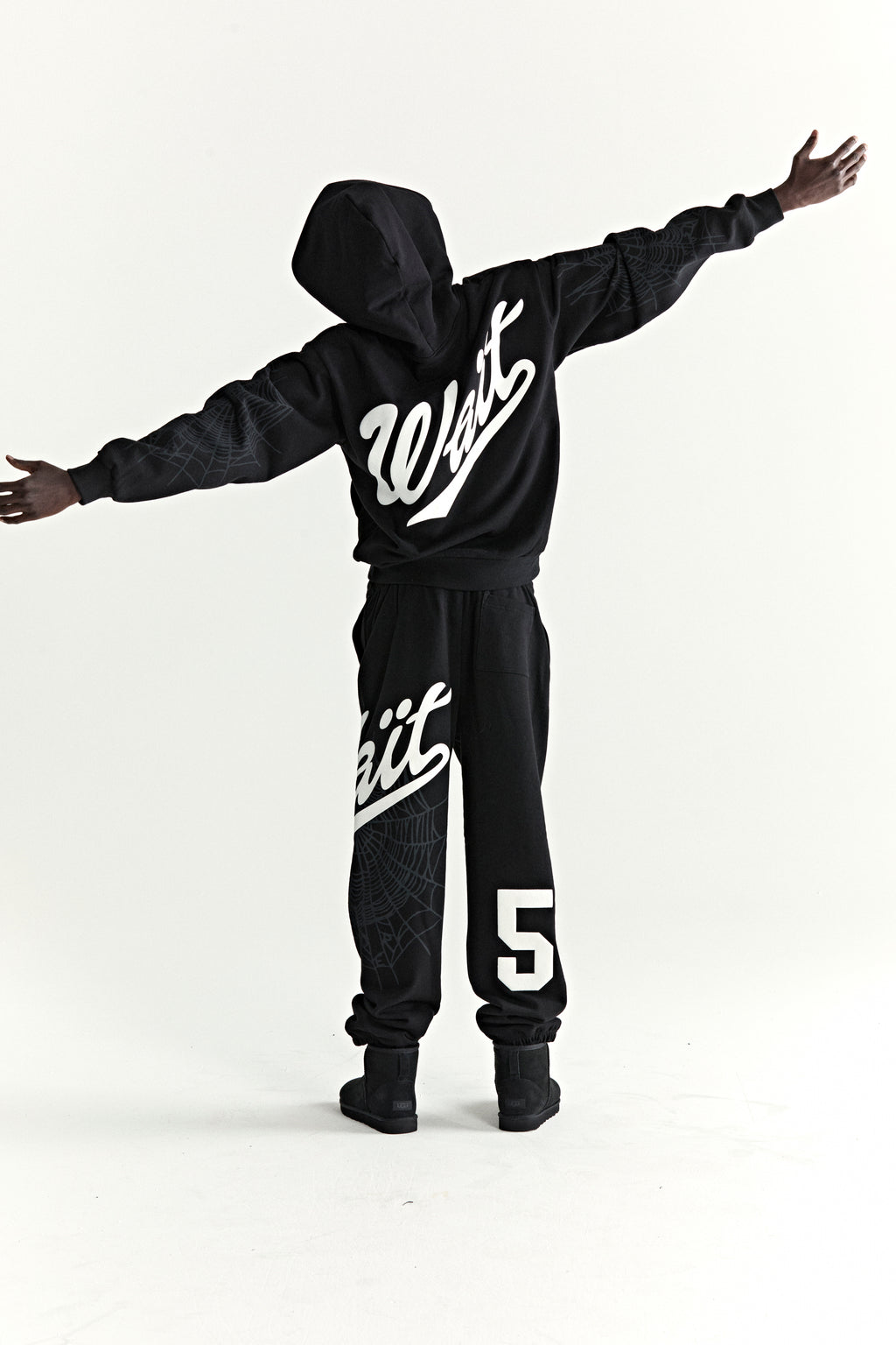 Black 13oz cotton fleece hoodie and sweatpants with "Wait" script, "5" graphic, and web detail.