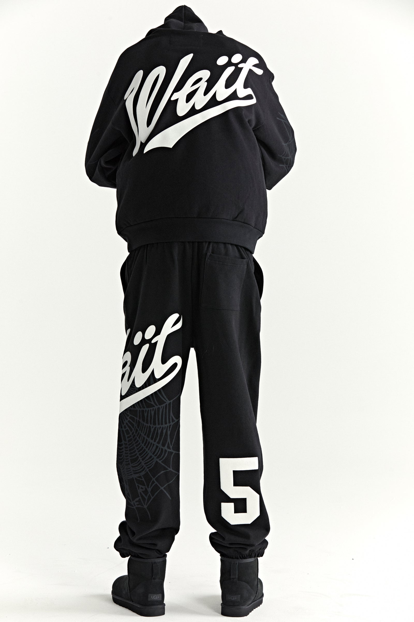 Black STADIUM HOODIE and sweatpants with "Wait" script, "5" graphic, and web detail.