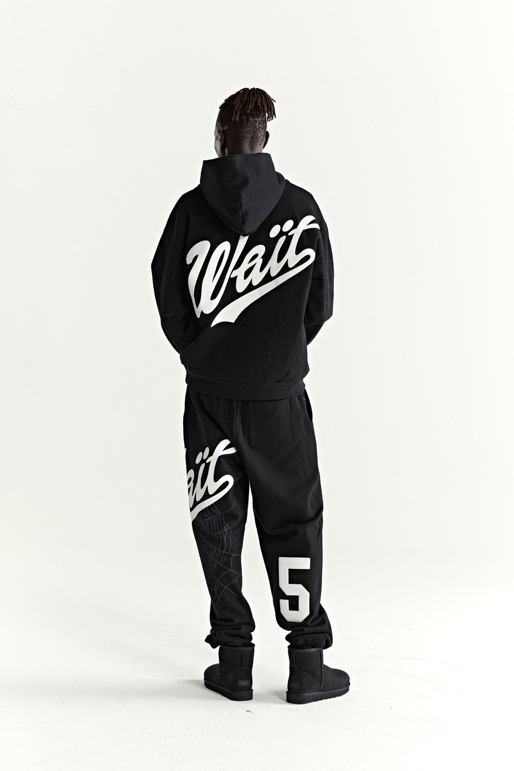 Black 13oz cotton fleece hoodie with "Wait" script on back, matching sweatpants with "5" and web detail.