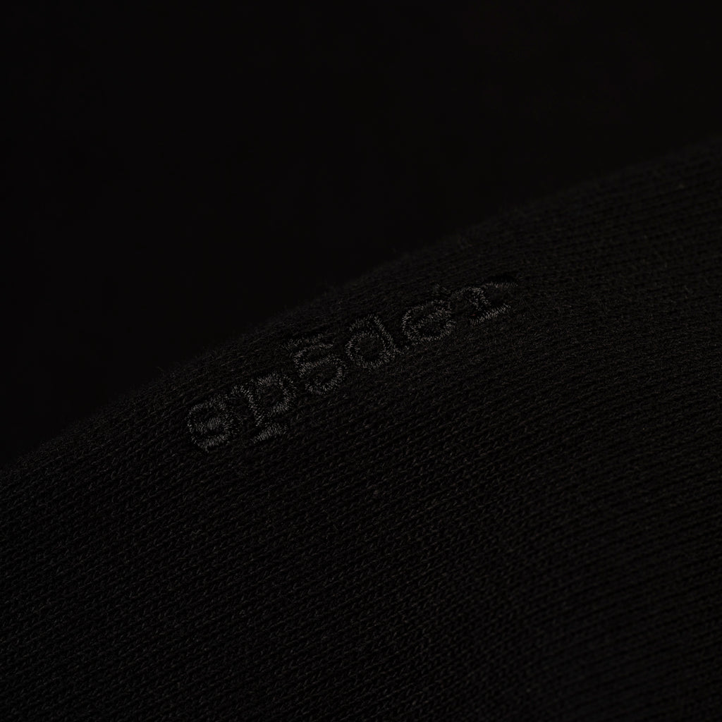 Close-up of a black 100% cotton fleece hoodie with subtle embroidered logo.