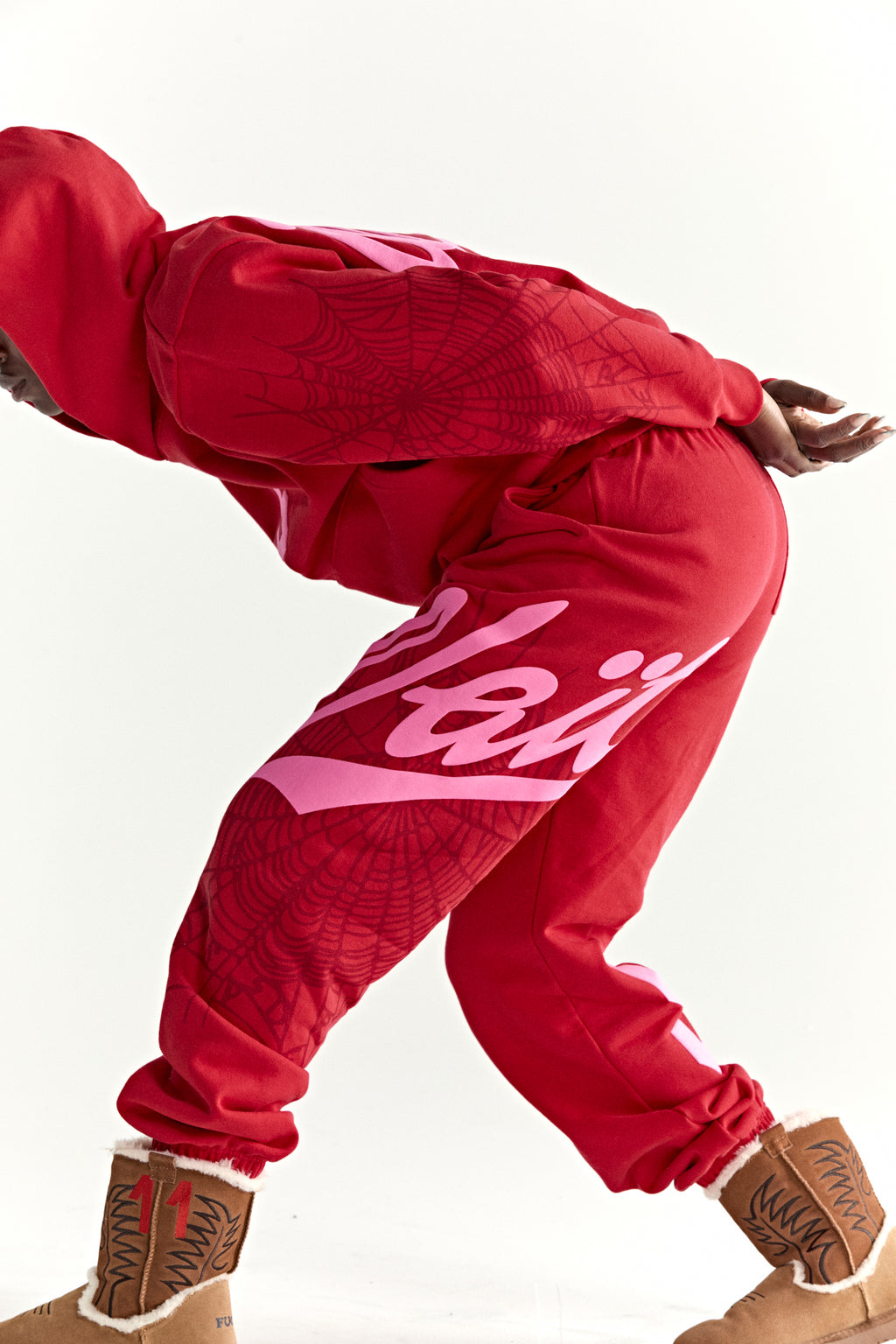 Red 13oz cotton fleece hoodie and sweatpants with pink puff print, spiderweb details, and script text.