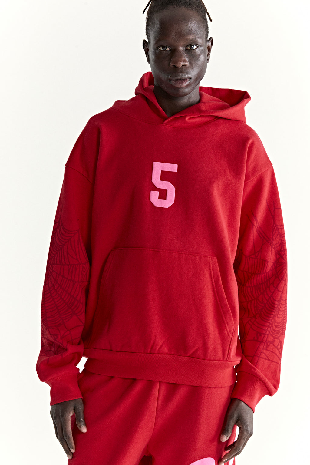 Red 13oz cotton fleece hoodie with pink '5' graphic, web detail on sleeves, and kangaroo pocket.