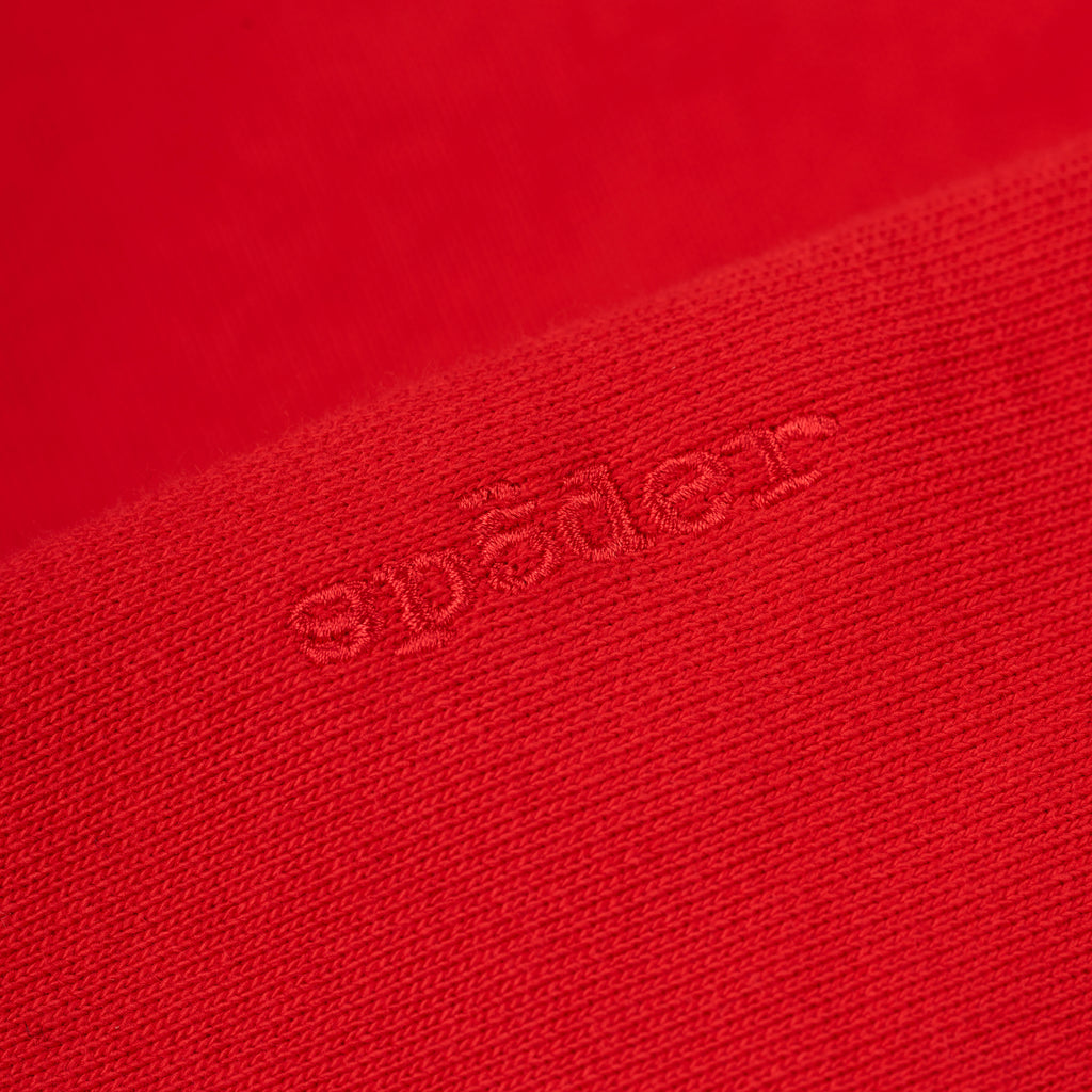 Close-up of a red 100% cotton fleece hoodie with embroidered "spades" text.