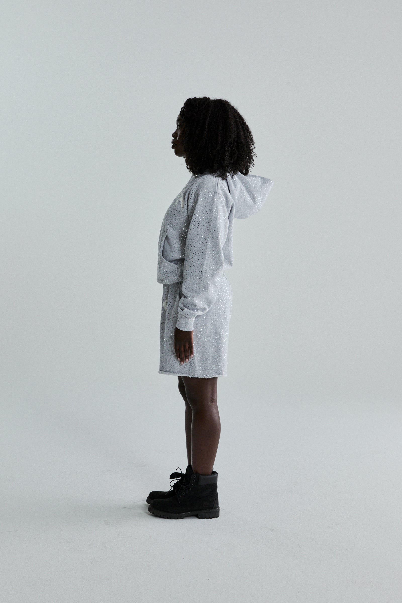 Light grey VVS HOODIE and shorts set with all-over tonal rhinestones, worn by a woman in profile.
