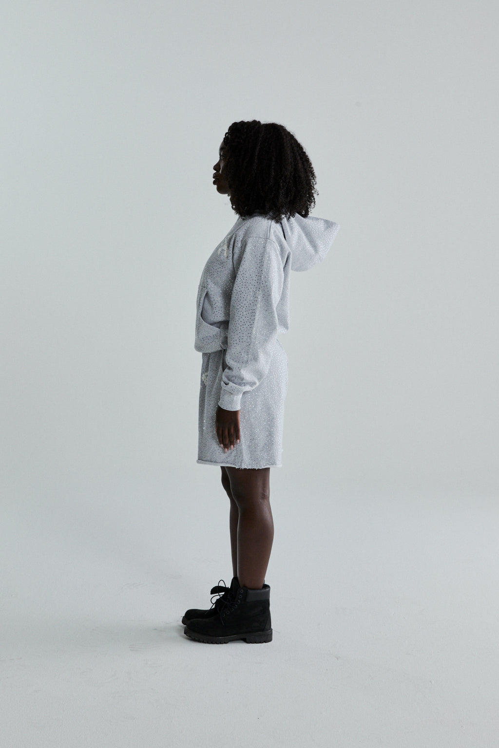 Light grey VVS HOODIE and shorts set with all-over tonal rhinestones, worn by a woman in profile.