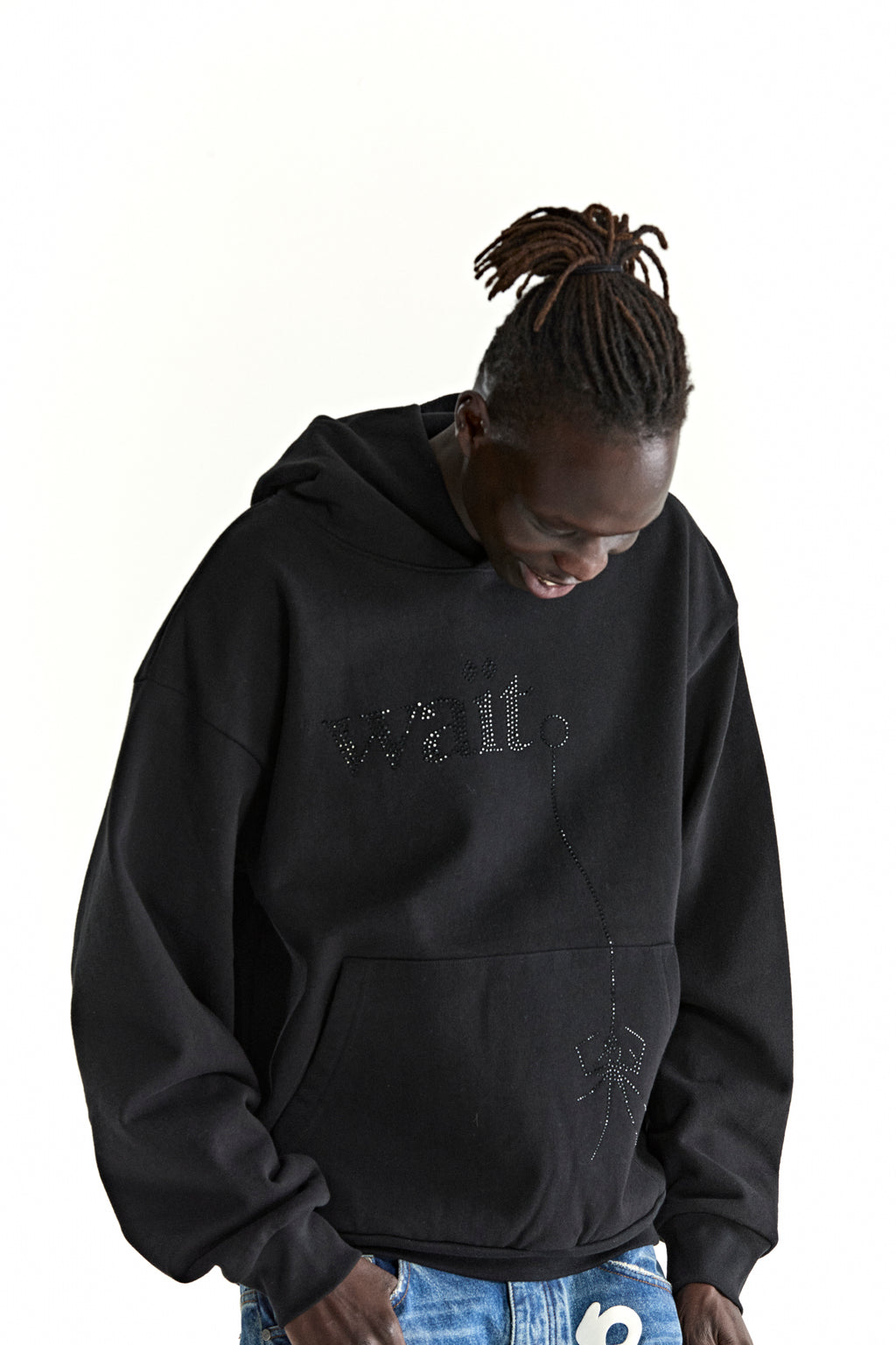 Black cotton fleece hoodie with rhinestone 'Wait' detail and spider design, worn by a person with dreadlocks.