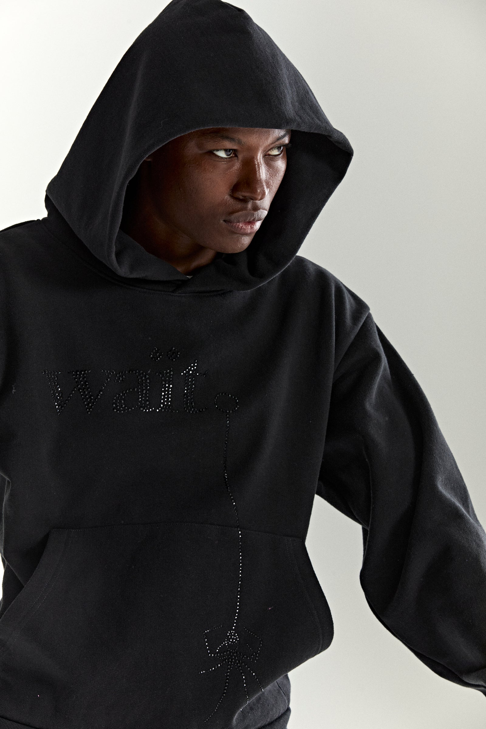 Black cotton fleece hoodie with rhinestone "Wait" detail and kangaroo pocket.