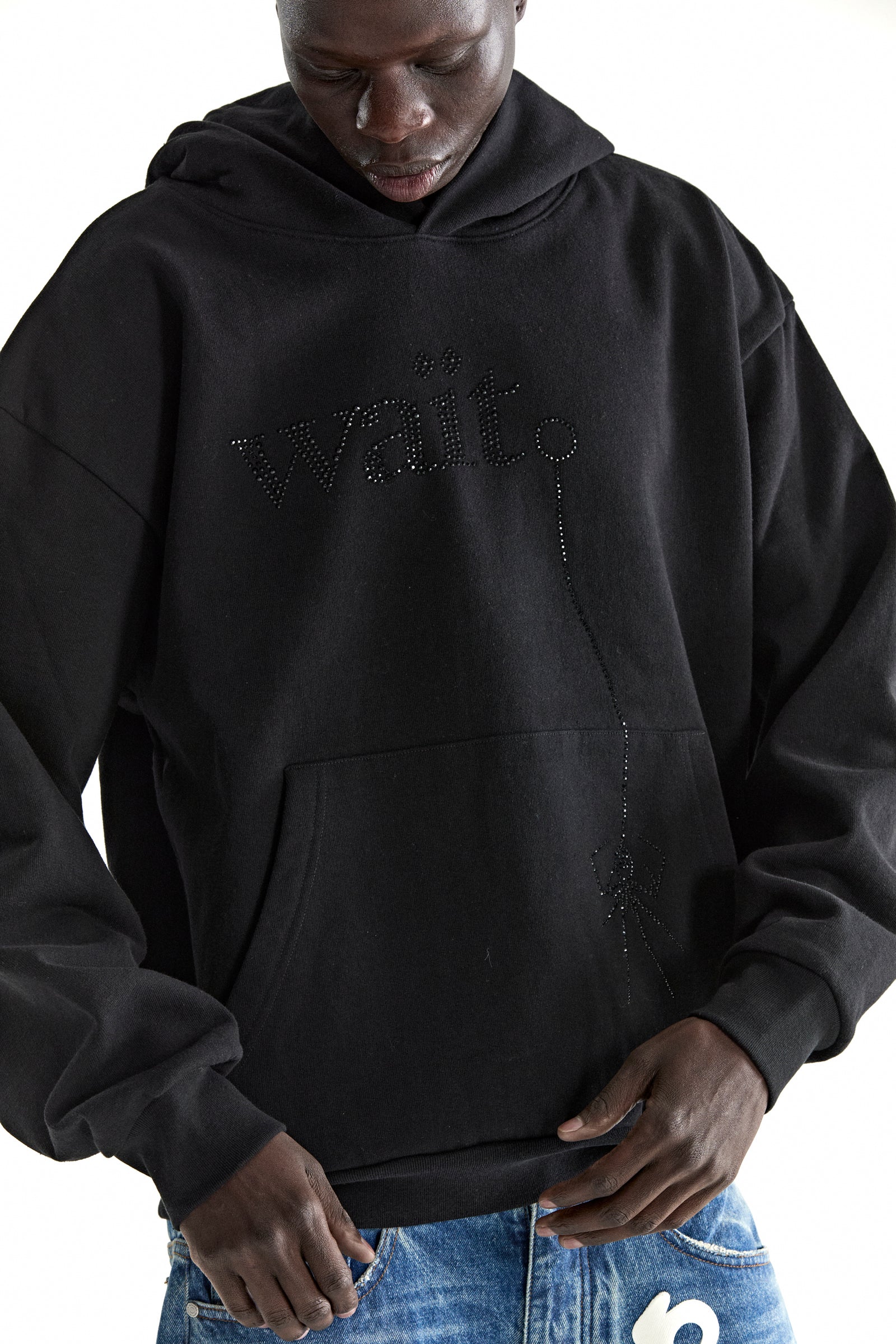 Black cotton fleece WAIT STONE HOODIE with rhinestone "Wait" detail, kangaroo pocket, and rib knit trim.