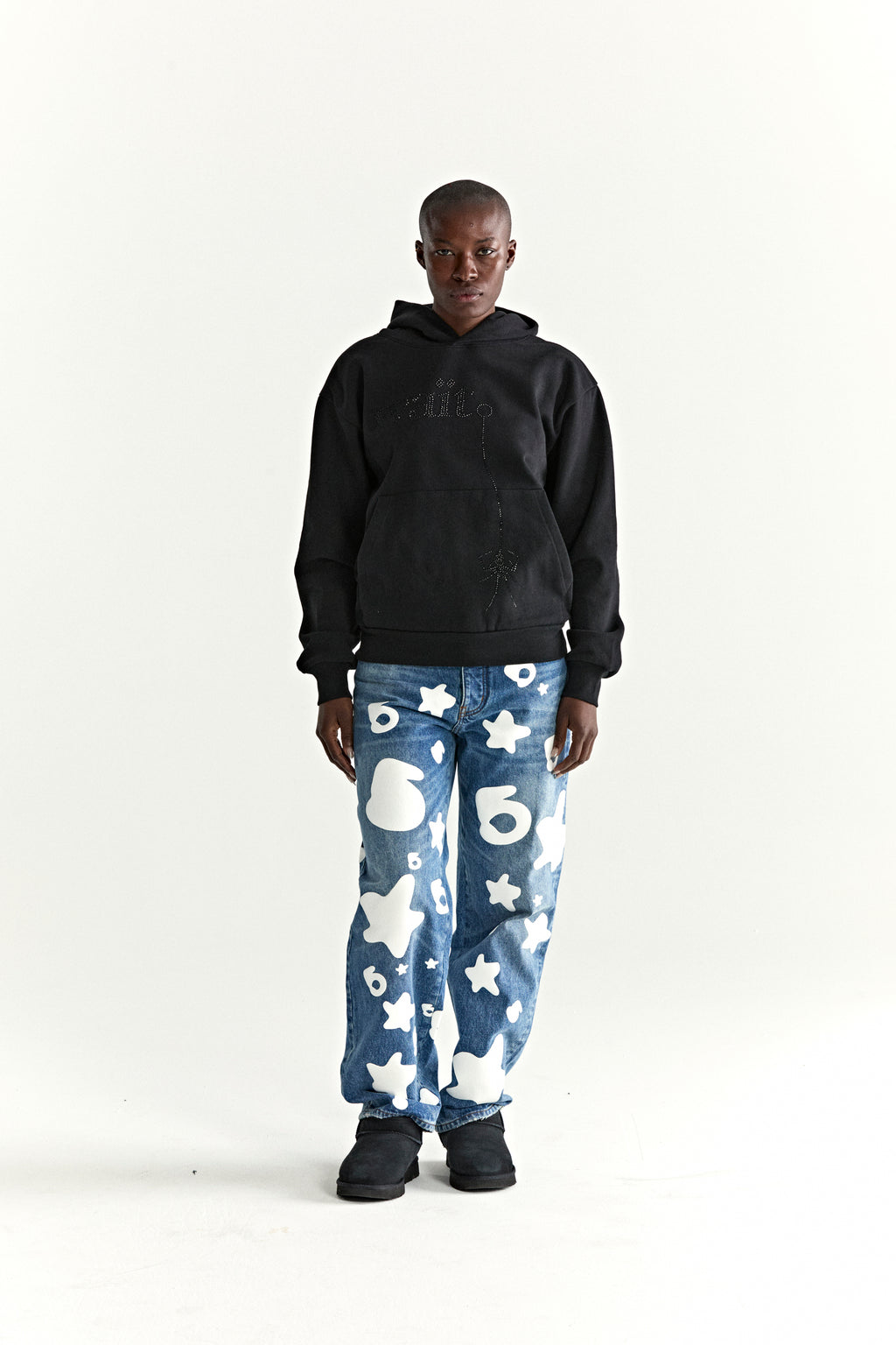 Black WAIT STONE HOODIE with rhinestone 'Wait' detail, kangaroo pocket, and rib knit trim, worn with patterned jeans.