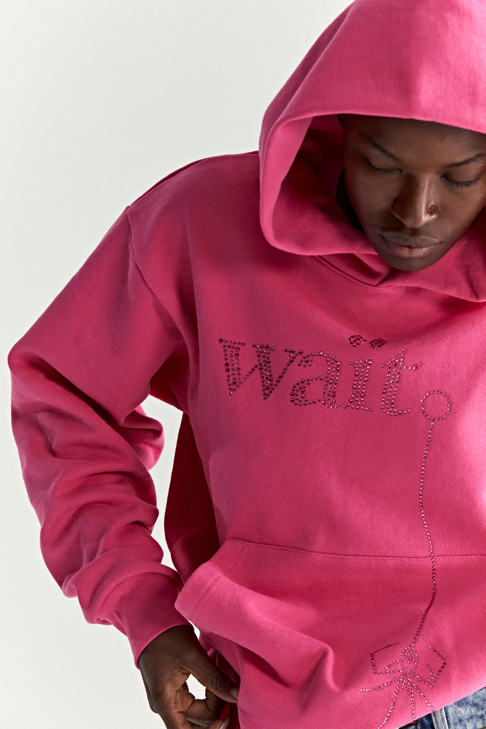 Pink cotton fleece hoodie with rhinestone "Wait" detail and spider graphic.