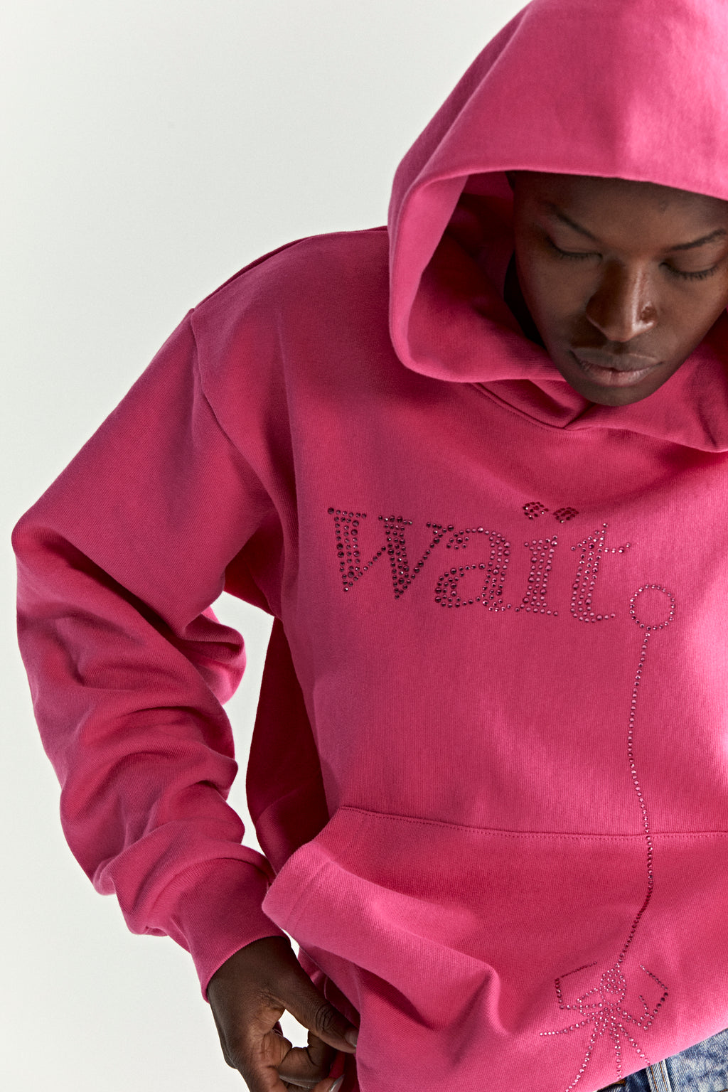 Pink cotton fleece hoodie with rhinestone "Wait" detail and spider graphic.